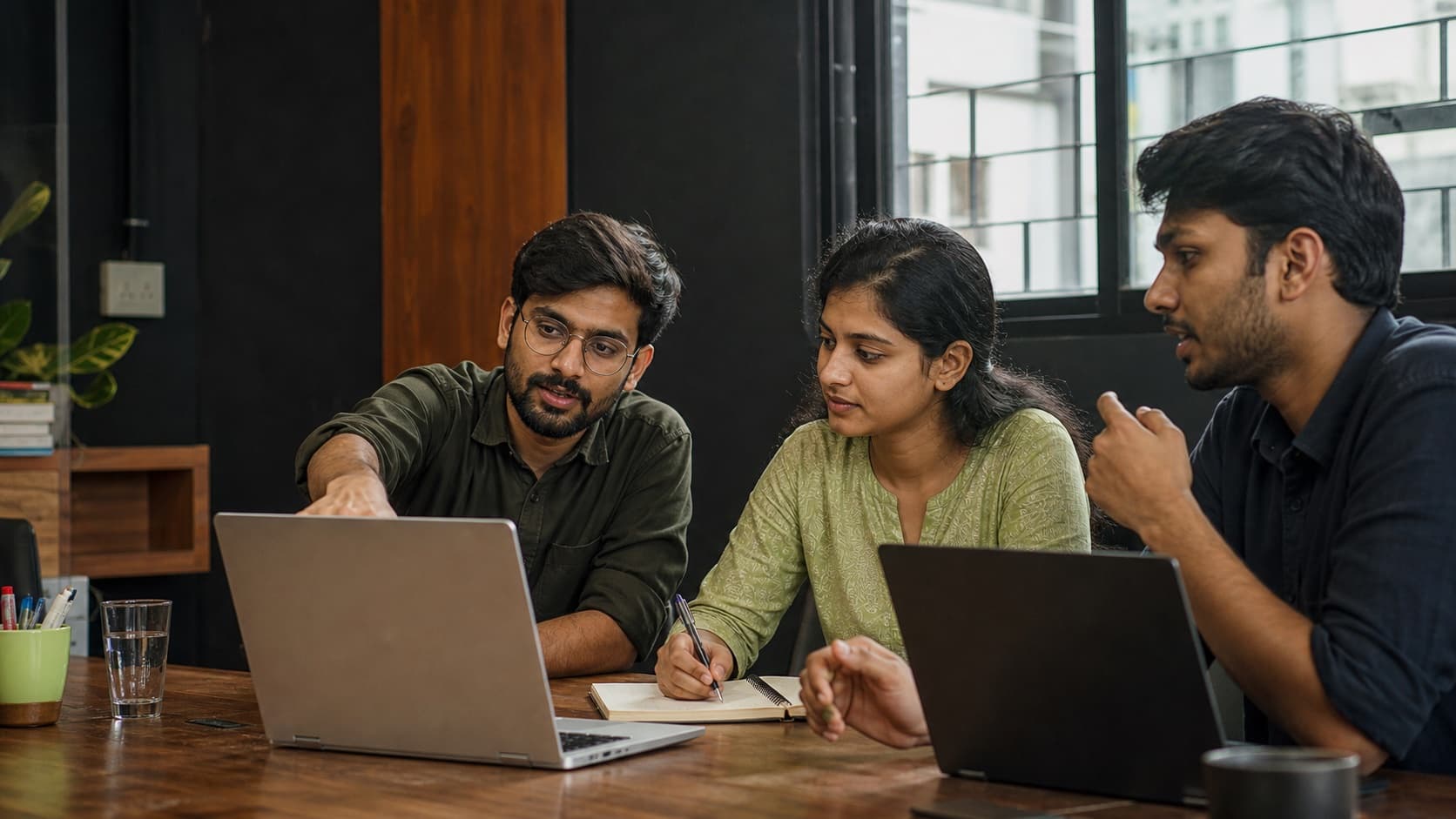 An illustrative scene of colleagues reviewing work around a shared laptop